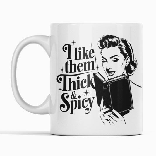 White mug black print. Woman reading book. Text I like them thick and spicy.