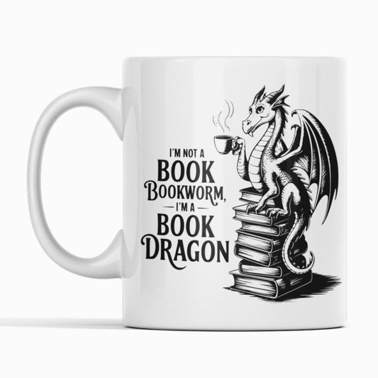 White mug with a dragon sat on books. Text I'm not a bookworm I'm a book dragon.