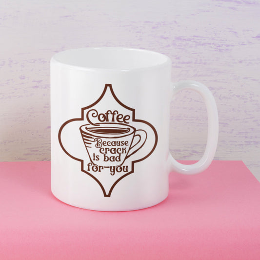 White mug with brown coffee-themed design on a pink surface with a light purple background